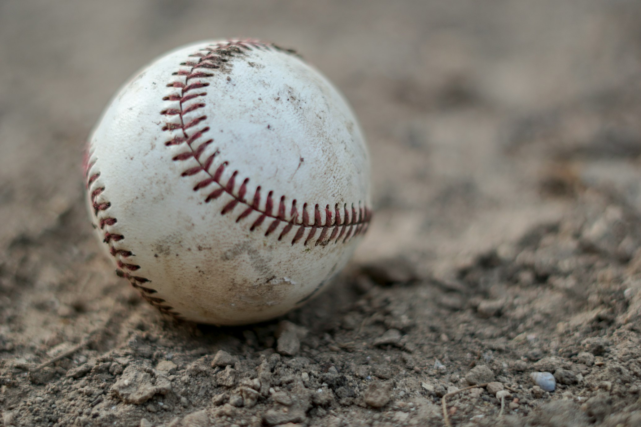 Closeup photo of a baseball sitting in the dirt