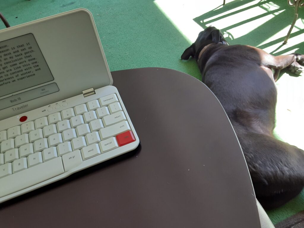 A phot from the author's perspective of his keyboard in the foreground and his dog laying in the sun in the background